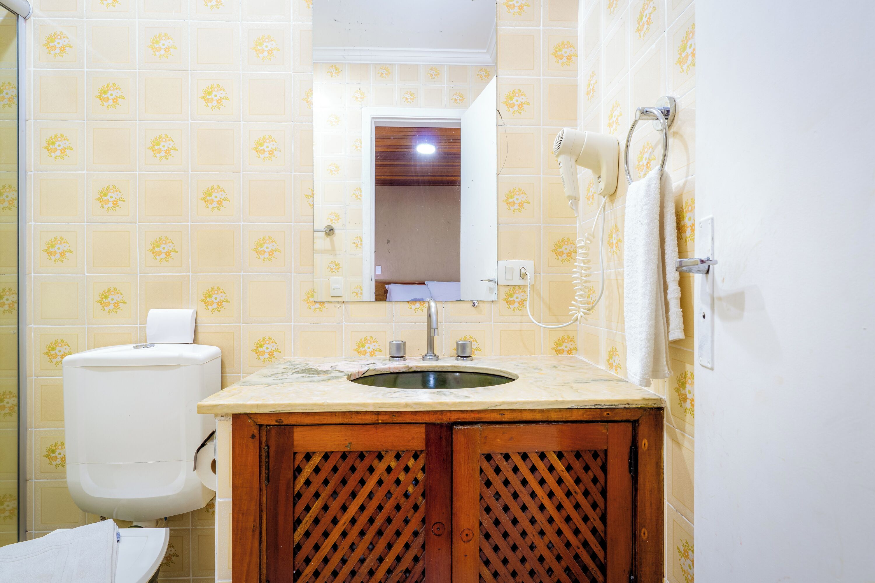 A bathroom with a toilet, sink, and mirror.