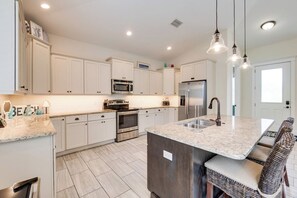 Una cocina moderna con armarios blancos, electrodomésticos de acero inoxidable y encimera de granito.
