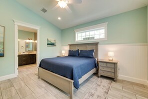 A bedroom with a bed, nightstands, a window, and a door leading to a bathroom.