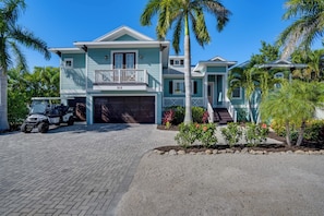 A two-story house with a garage, a driveway, and a golf cart parked in front.