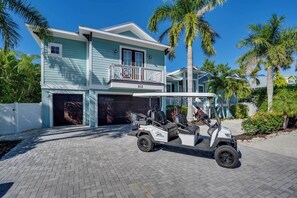 Een tweelaags huis met een garage, een balkon en een golfkarretje ervoor geparkeerd.