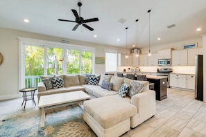 A modern kitchen with a central island, pendant lighting, and a ceiling fan.