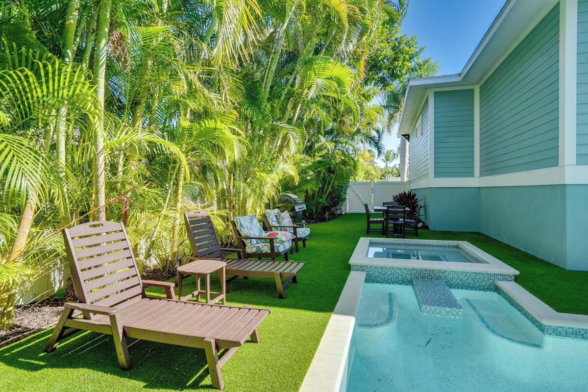 A pool area with artificial grass, lounge chairs, and a hot tub.