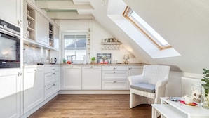 A modern kitchen with white cabinetry, a wooden floor, and a skylight.