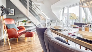 A modern loft with a dining area, a red leather chair, and a staircase.