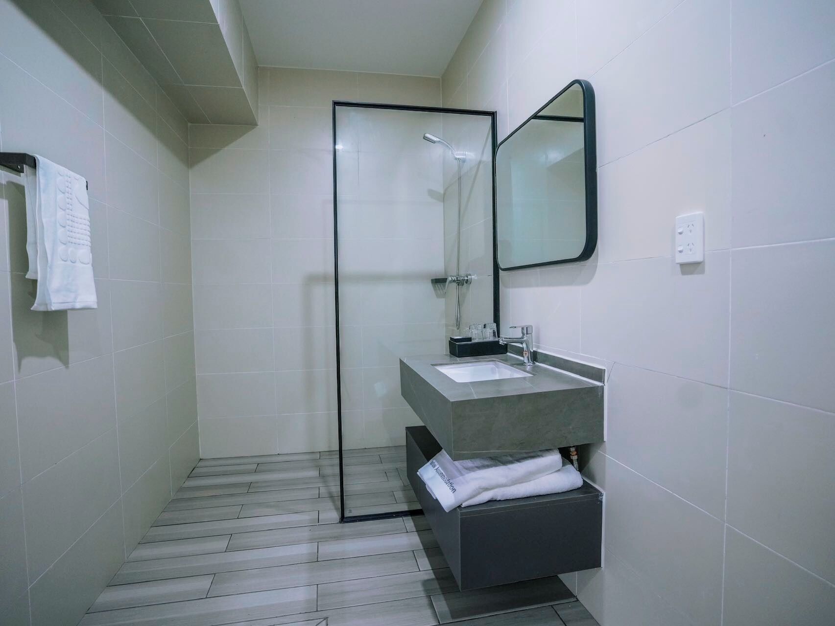 Un baño moderno con cabina de ducha de vidrio, lavabo con toallero y espejo.