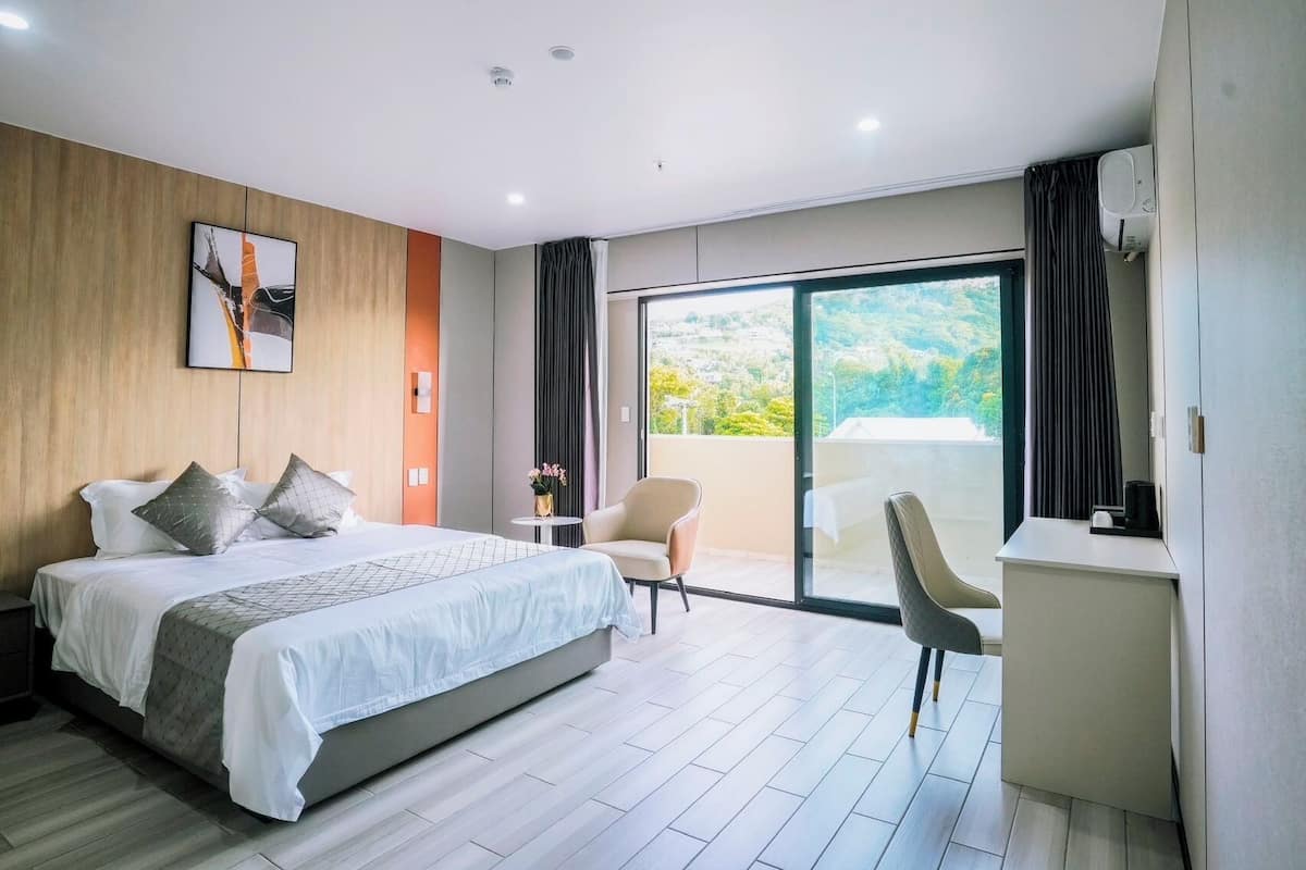 A modern hotel room with a large bed, a desk, and a chair.