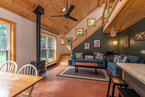 A cozy living room with a fireplace, a sofa, a dining table, and a staircase.