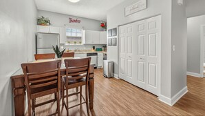 Une cuisine moderne avec des meubles blancs, une table à manger avec des chaises et un réfrigérateur.