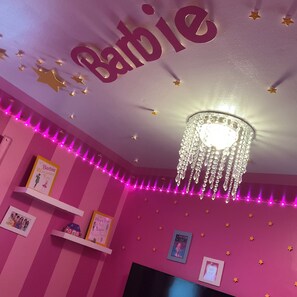 A room with pink walls, a ceiling with 'Barbie' written on it, star decorations, a chandelier, and shelves with framed pictures. - Luxury 3-Bedroom Home with Themed Rooms & Private Party Space (Chicago)