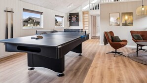 Un espacio interior moderno con mesa de billar, asientos cómodos y dardos.