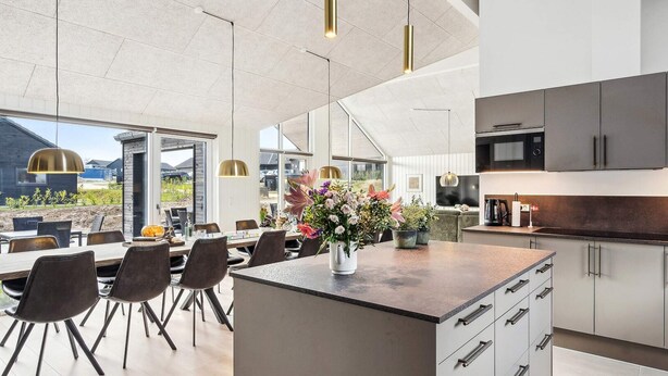 Una cocina moderna con una isla central, electrodomésticos de acero inoxidable y una zona de comedor con sillas y mesa.