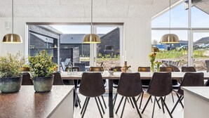 Un comedor moderno con una mesa larga, sillas negras y plantas en macetas.