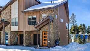 Un edificio moderno con fachada de piedra, revestimiento de madera y tejado cubierto de nieve.