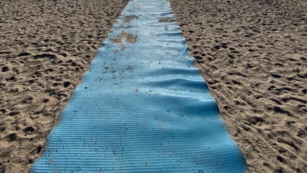 A beach with a blue mat leading to the water, clear skies, and a distant pier. - ARCA  Cozy Cabin-Innisfil Beach (Innisfil)