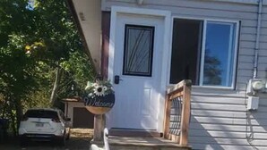 A house with a front porch, a welcome sign, and a swan statue. - ARCA  Cozy Cabin-Innisfil Beach (Innisfil)