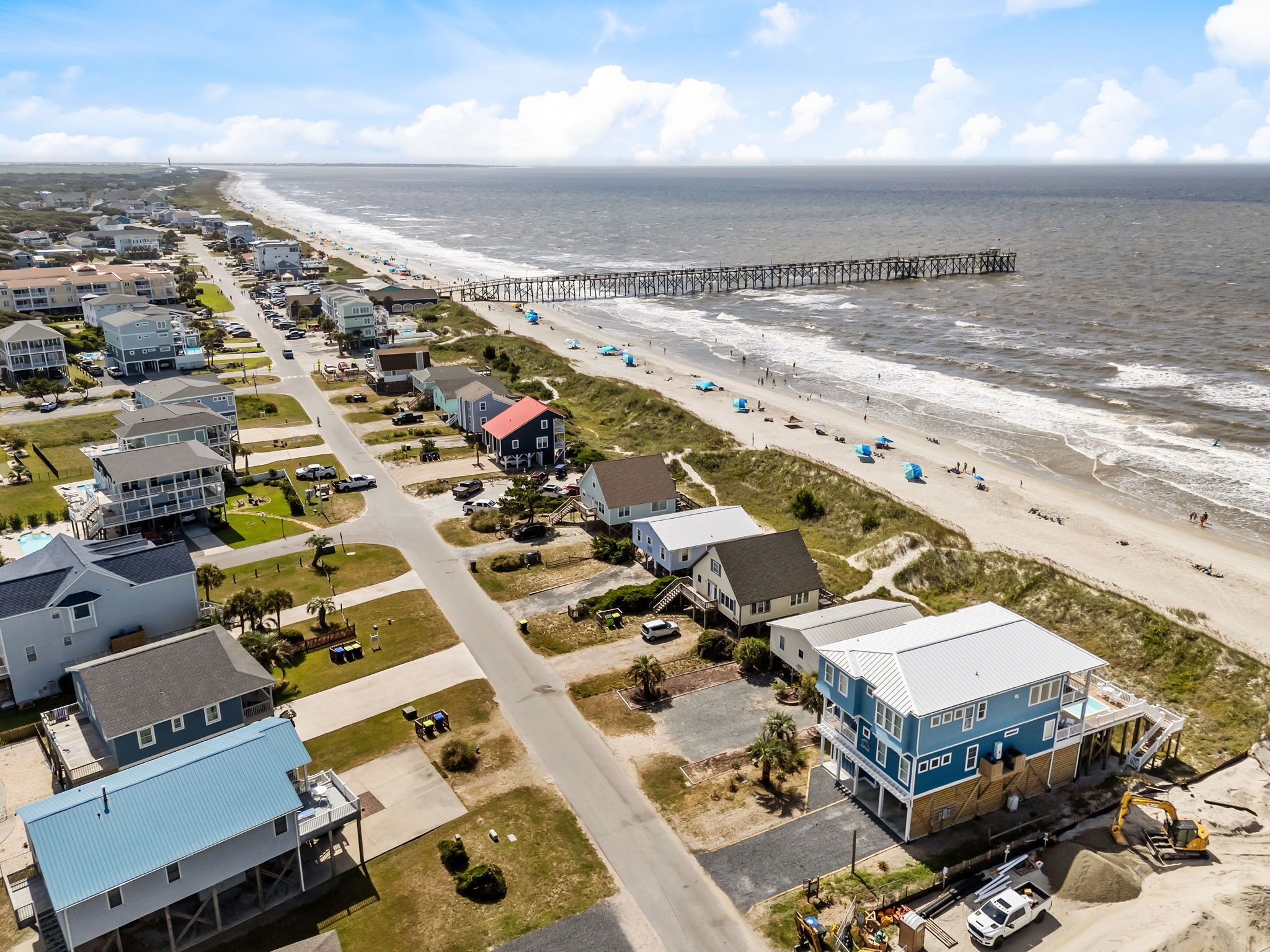 A coastal residential area with beachfront properties, a pier, and a road leading to the beach.