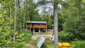 A cabin with a stone foundation, a wooden deck, and a covered patio area. - Lakeside Cabin "Serenity" (Town of Silver Cliff)