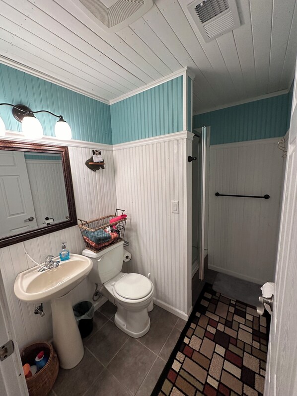 Un baño con lavamanos blanco, inodoro y zona de ducha.