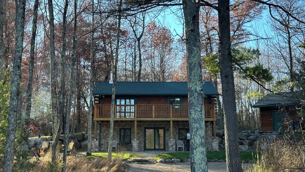 A two-story log cabin with a stone foundation, surrounded by a forest. - Lakeside Cabin "Serenity" (Town of Silver Cliff)