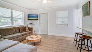 A living room with a sofa, coffee table, and two bar stools. - Charming cottage in delightful Stuart with AC, WiFi (Stuart)