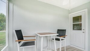 A small room with a white door, a window, and a table with two chairs. - Charming cottage in delightful Stuart with AC, WiFi (Stuart)