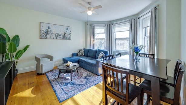 Un salon moderne avec un canapé bleu, une table à manger et un ventilateur de plafond.