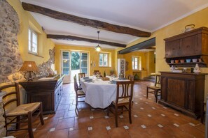 Una sala da pranzo con un tavolo grande, sedie, una lampada e un armadietto in legno.