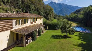 Una vila amb teulada de rajola, piscina i un paisatge de muntanyes al fons.