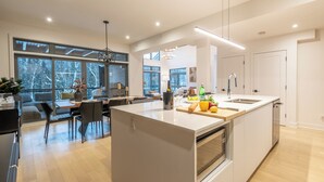 Eine moderne Küche mit einer großen Kochinsel, integrierten Geräten und großen Fenstern mit Blick ins Freie.