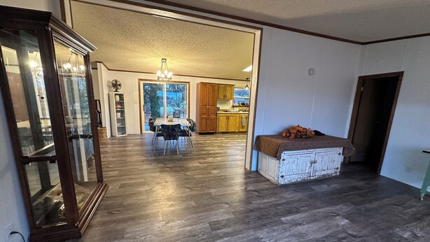 Amplia sala de estar con una mesa y sillas de comedor, un armario blanco y vista hacia la cocina.