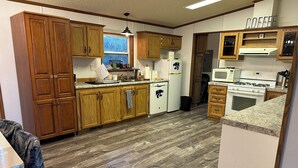 Una cocina con armarios de madera, lavavajillas, refrigerador, estufa y microondas.