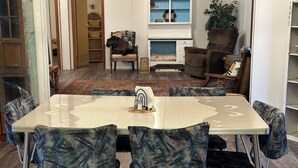 Un comedor con una mesa, sillas, chimenea y una estantería.