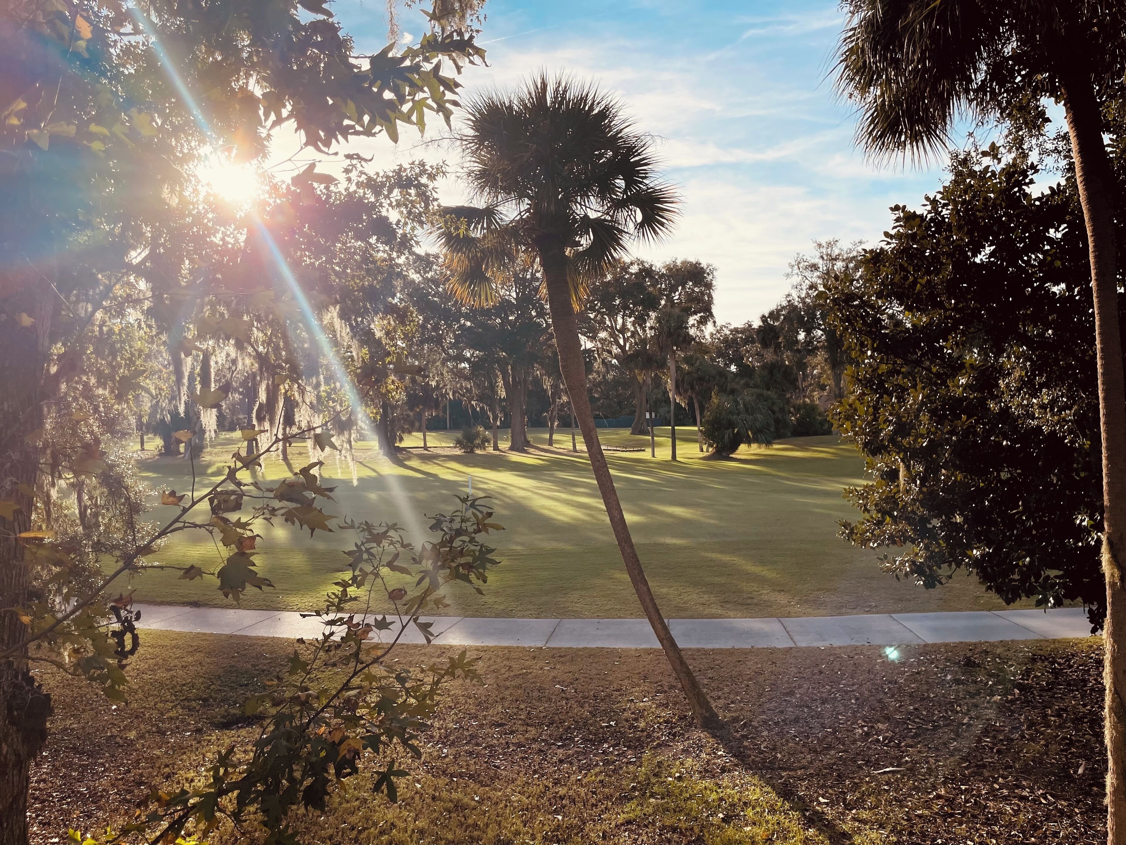 A golf course with a well-maintained fairway, surrounded by trees and a clear sky.