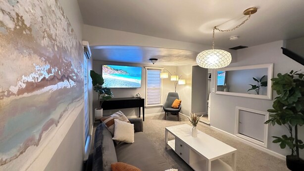 Un salón con sofá, mesa de centro y televisor mostrando una escena de playa.