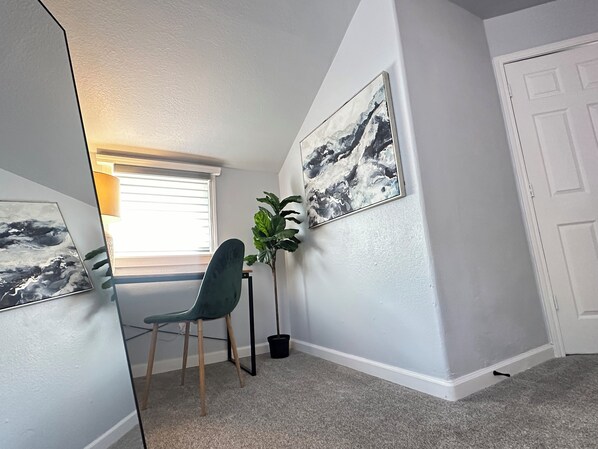 A room with a chair, a potted plant, and a painting on the wall. - The Oasis - Your Luxury 2BR/1.5BA Home in Downtown Modesto (Modesto)