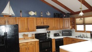 A kitchen with wooden cabinets, a black refrigerator, a stove, a microwave, and a sink.