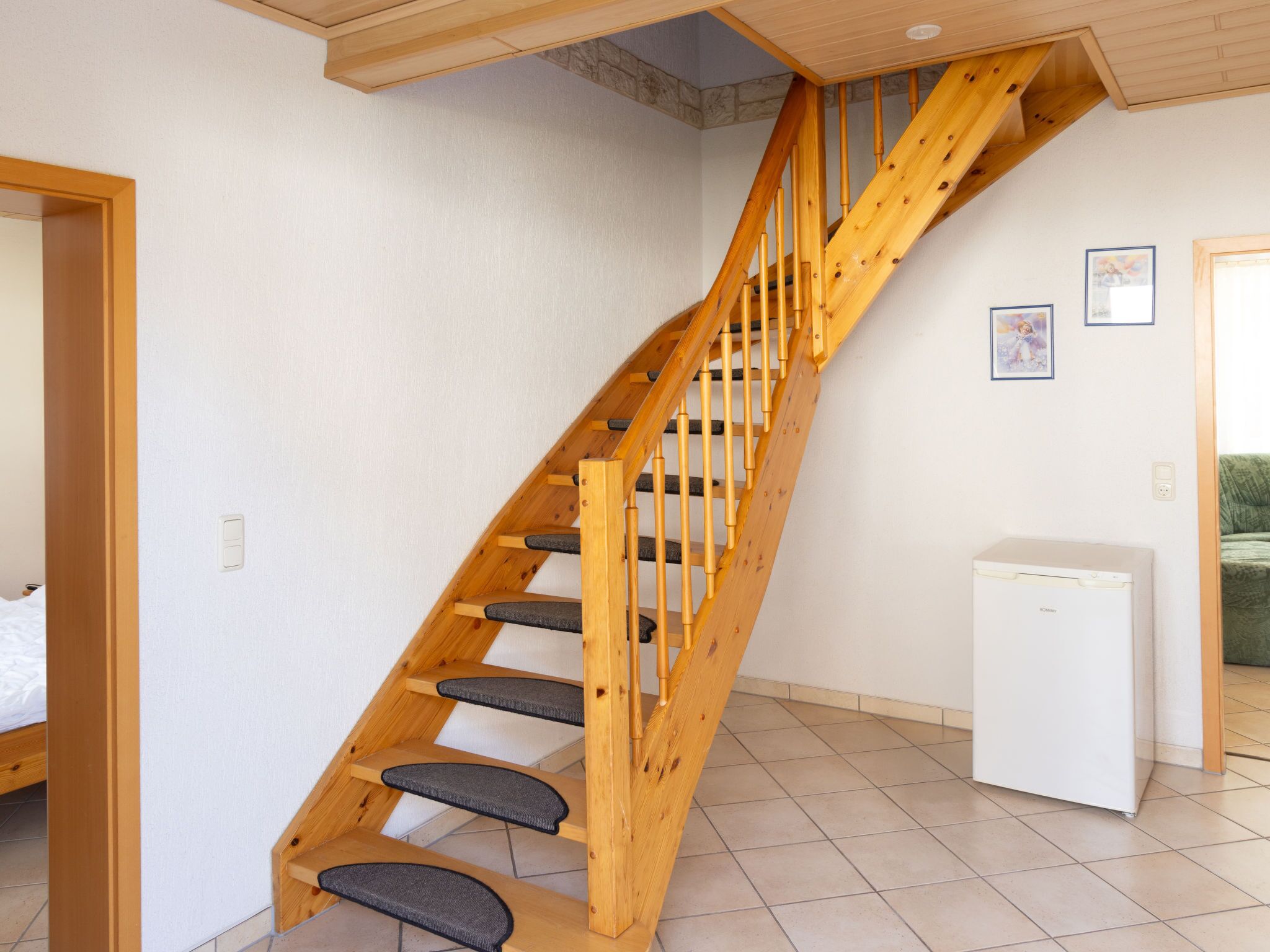 A wooden staircase with grey steps and a white wall.