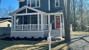 A two-story house with a porch, a red door, and a mailbox. - Beautiful New 5 BR in Bethany West - EV Charging (Bethany Beach)