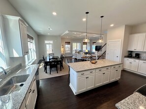 Una cocina amplia con encimeras de granito, una isla central y muebles de color blanco.