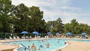 A swimming pool area with multiple pools, lounge chairs, and umbrellas. - Beautiful New 5 BR in Bethany West - EV Charging (Bethany Beach)