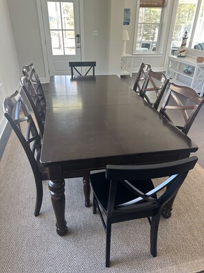 A dining room with a large rectangular table surrounded by six wooden chairs.
