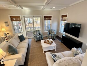 Una sala de estar con dos sofás, una mesa de centro, un televisor y una ventana con vistas a una terraza.