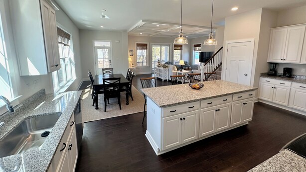 A spacious kitchen with granite countertops, a central island, and white cabinetry. - Beautiful New 5 BR in Bethany West - EV Charging (Bethany Beach)