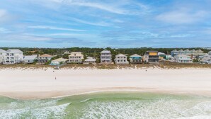 Une propriété située en bord de mer, comprenant plusieurs maisons, une plage de sable et une vue sur l’océan.