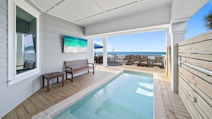 Un espace piscine doté d’une terrasse en bois, d’un banc et offrant une vue sur l’océan.