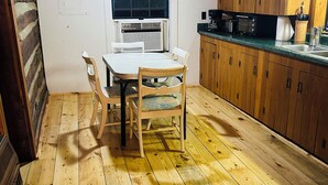 Cozinha com painéis de madeira, mesa e cadeiras, uma janela e armários de madeira.