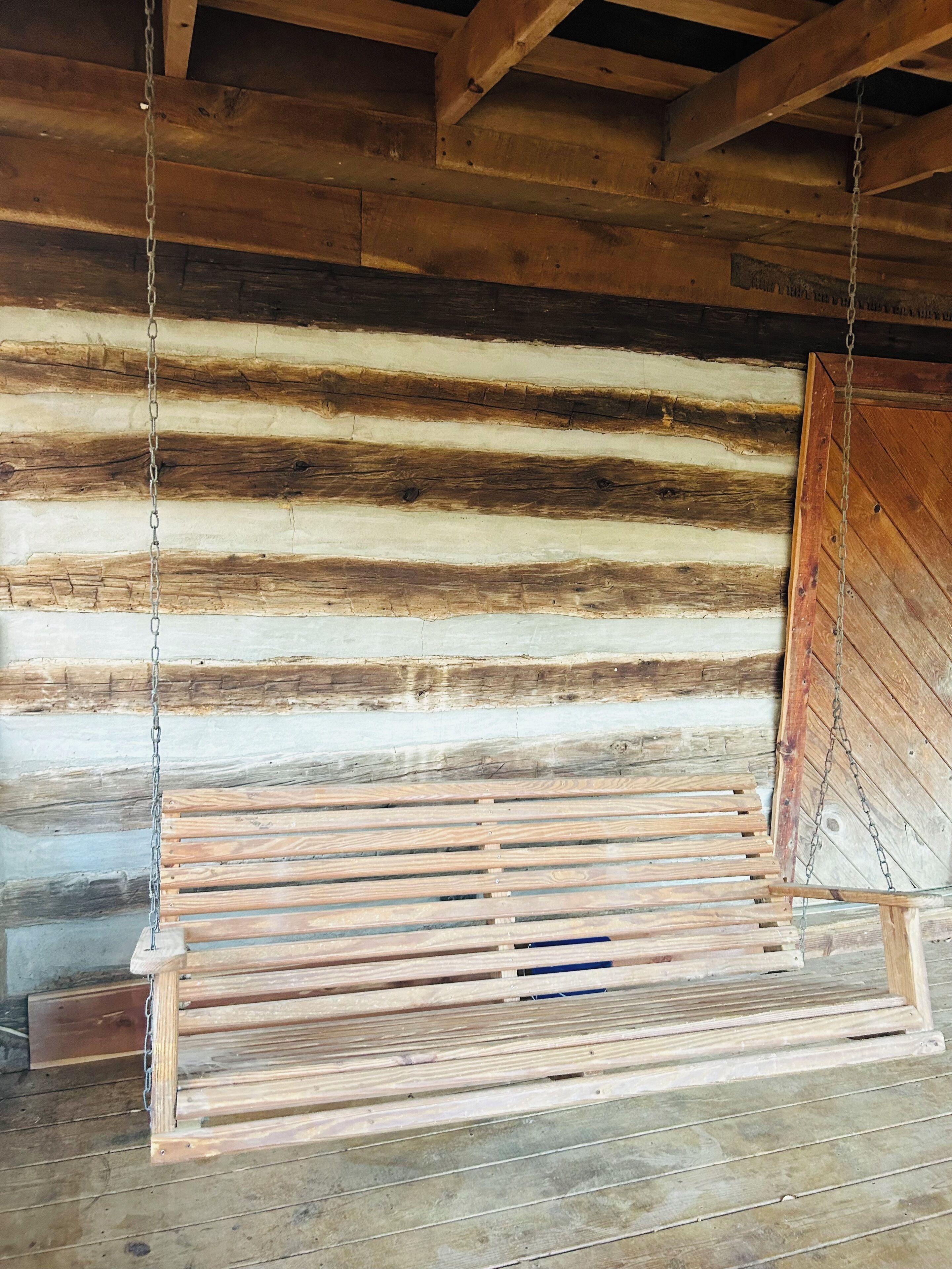 Interior rústico de una cabaña de madera con un columpio de madera colgando del techo.