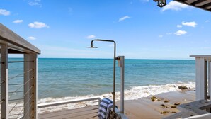 A wooden deck with a metal showerhead overlooking a beach. - Exclusive Luxury Beachfront Home With Two Separate Units (Santa Barbara)