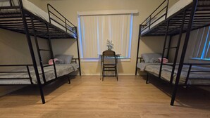 A room with two bunk beds, a small table, and a chair.